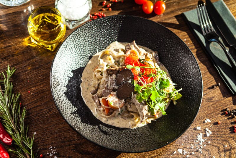 Black Angus beef tagliatelle pasta with fresh black truffles and parmegano. Delicious healthy traditional food closeup served for lunch in modern gourmet cuisine restaurant.