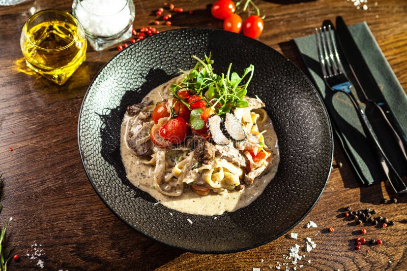 Black Angus beef tagliatelle pasta with fresh black truffles and parmegano. Delicious healthy traditional food closeup served for lunch in modern gourmet cuisine restaurant.