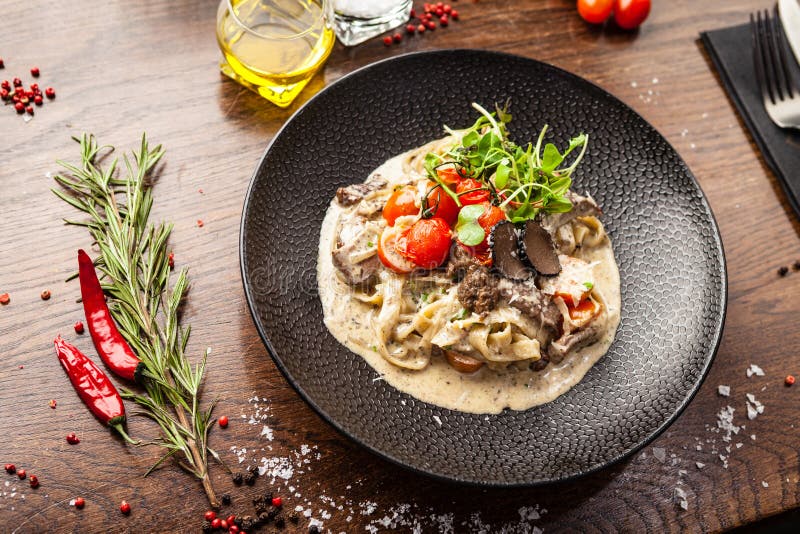 Black Angus beef tagliatelle pasta with fresh black truffles and parmegano. Delicious healthy traditional food closeup served for lunch in modern gourmet cuisine restaurant.