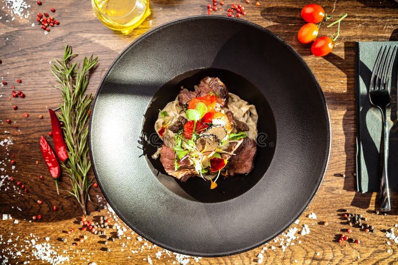 Black Angus beef tagliatelle pasta with fresh black truffles and parmegano. Delicious healthy traditional food closeup served for lunch in modern gourmet cuisine restaurant.