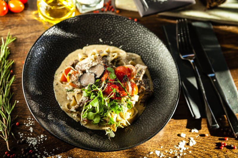 Black Angus beef tagliatelle pasta with fresh black truffles and parmegano. Delicious healthy traditional food closeup served for lunch in modern gourmet cuisine restaurant.