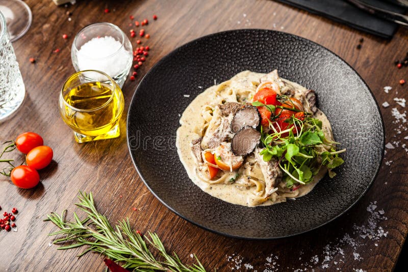 Black Angus beef tagliatelle pasta with fresh black truffles and parmegano. Delicious healthy traditional food closeup served for lunch in modern gourmet cuisine restaurant.