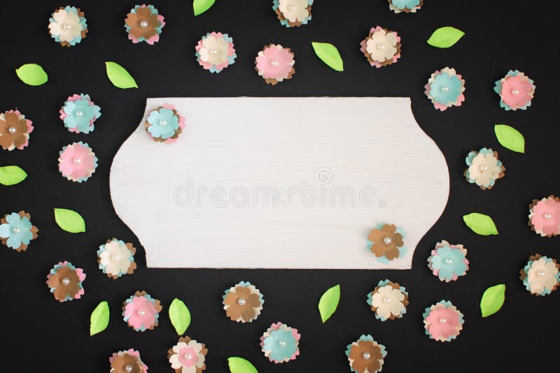 On a black background small flowers made of paper are randomly scattered. In the center is an empty plate with copy royalty free stock images On a black background small flowers made of paper are randomly scattered. In the center is an empty plate with copy royalty free stock images