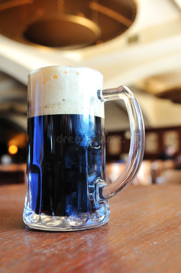 Pint of black beer on the table inside tavern