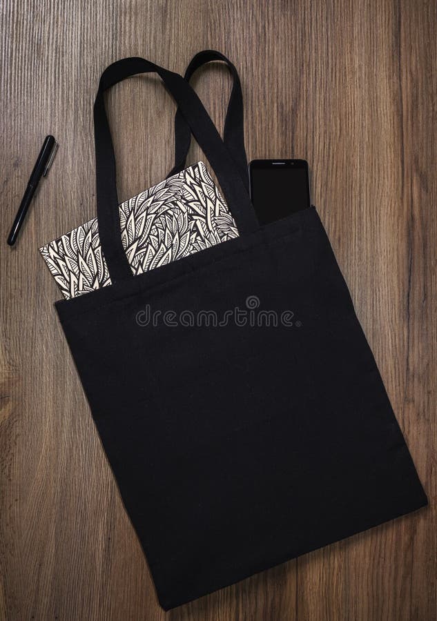 Black blank cotton eco tote bag with smartphone and notebook, design mockup. Black blank cotton eco tote bag with smartphone and notebook, design mockup.