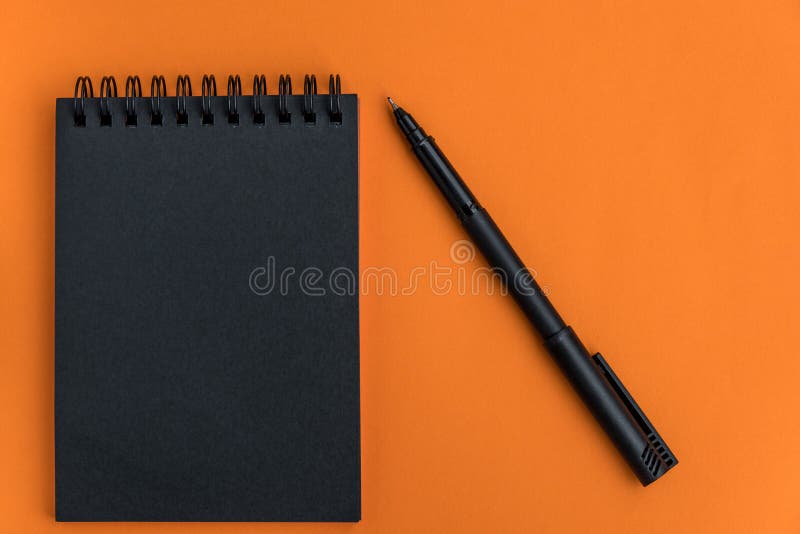 Black blank notebook and pen on an orange background. Minimalistic halloween celebration design. Mock up. Flat lay. Top view, space for text. Notepad composition stock images, royalty-free photos and pictures