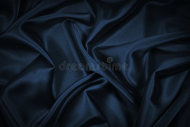 Black blue abstract background. Dark blue silk satin texture background. Beautiful wavy soft folds on the surface of the fabric.
