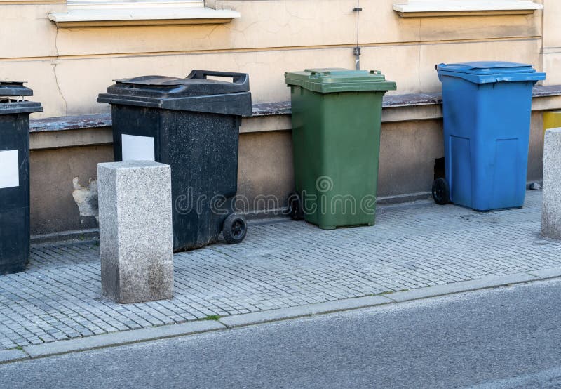 Black, blue, yellow, green garbage containers in city.  Separate waste, preserve the environment concept. Segregate waste