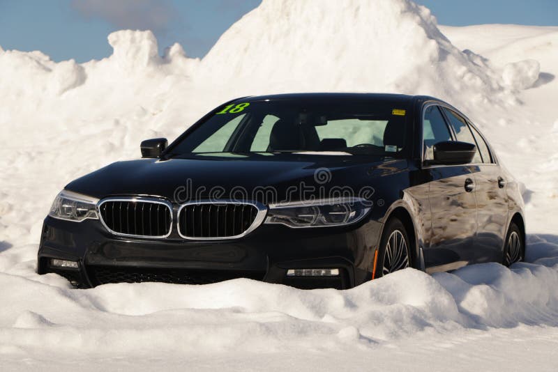 Черный BMW 5 серии в снегу. Вид сбоку автомобиля BMW. Роскошный и элегантный автомобиль. Автомобиль зимой на заснеженной дороге Сток-изображения без роялти