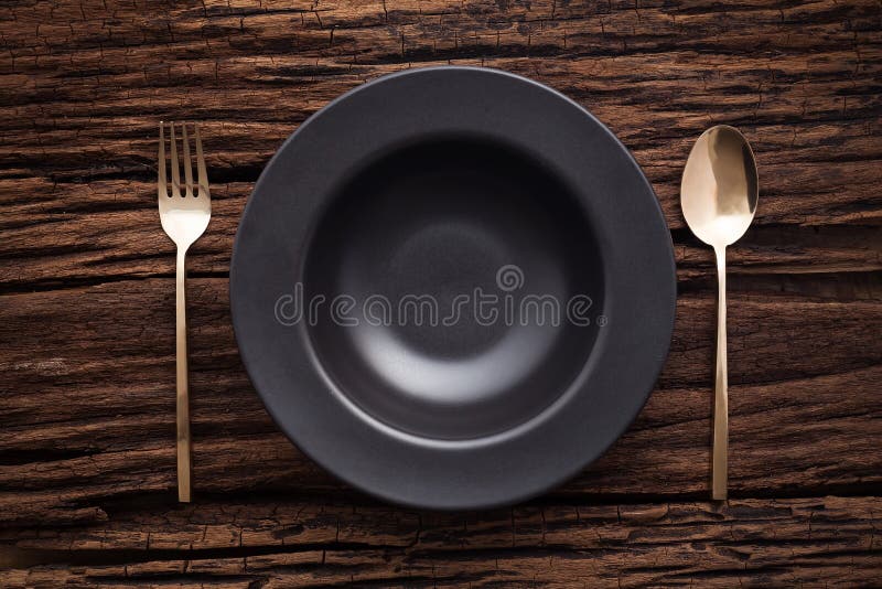 Black bowl plate fork spoon on wooden table background royalty free stock photo