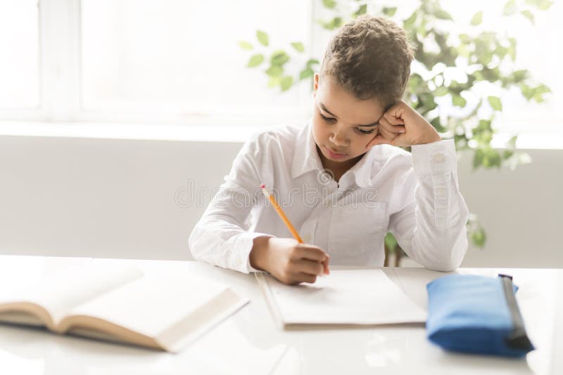 A cute Black boy doing homework at home stock images A cute Black boy doing homework at home stock images
