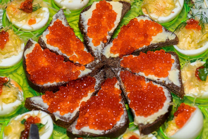Black Bread with Caviar on a Tray Around Stuffed Chicken Eggs. Canapes