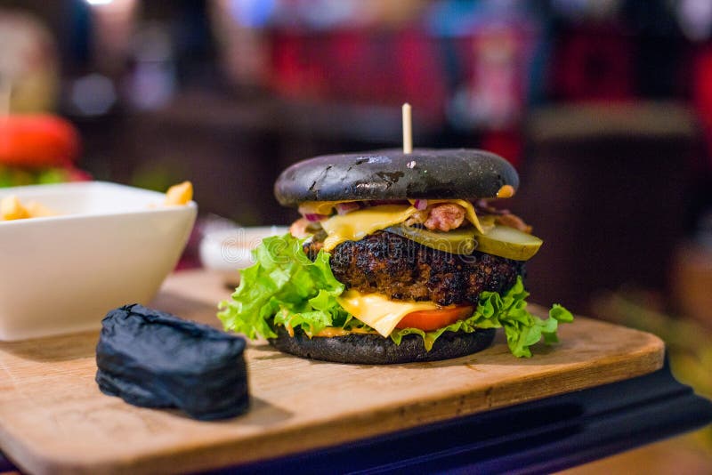 black burger on wooden board. Toned picture stock photo black burger on wooden board. Toned picture stock photo