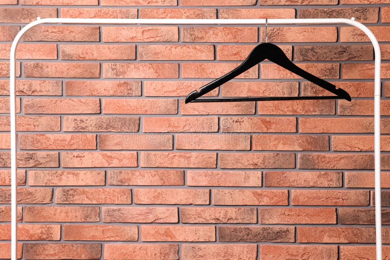 Black Clothes Hanger on Rack Near Red Brick Wall. Space for Text Stock