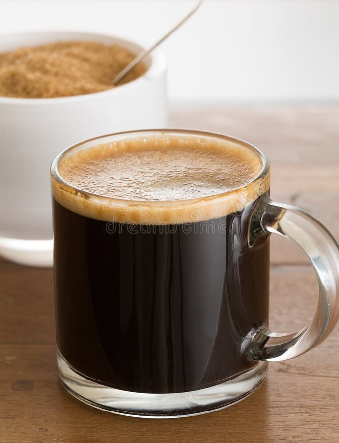 Black coffee and froth in glass mug with sugar