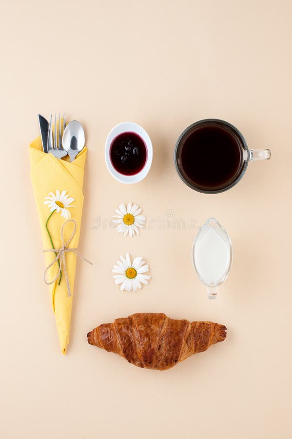 Black coffee, milk, fresh croissant and jam on a light yellow ba stock image