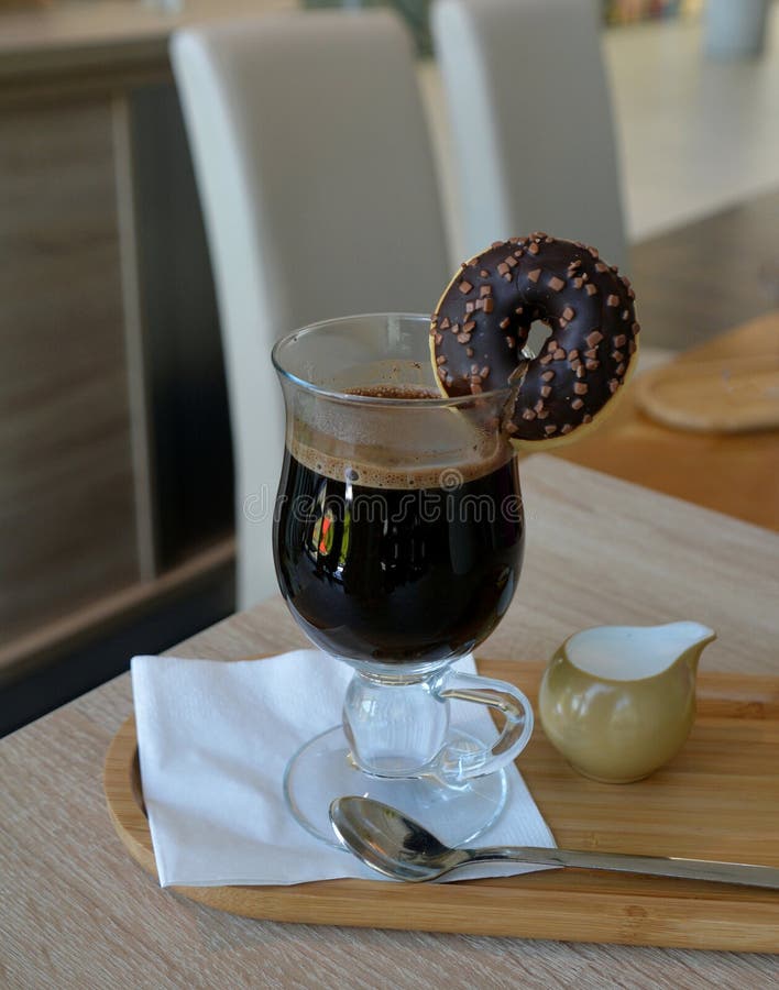 Black Coffee with Milk on a Glass Cup and Small Donut on a Wooden Table