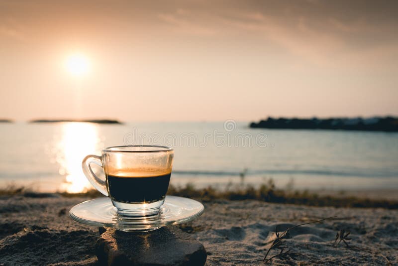 Black coffee ready to drink from mug on the beach outdoor picnic
