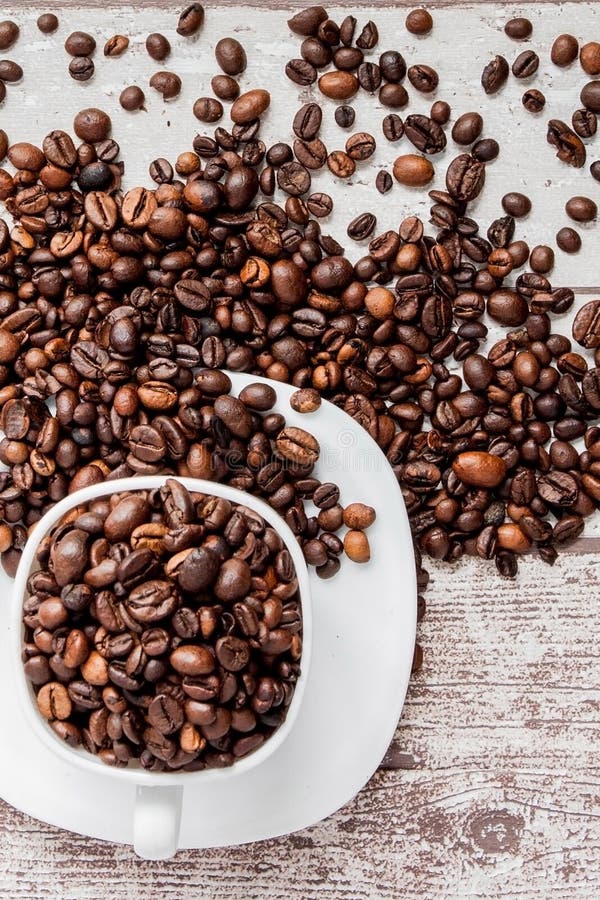Black coffee in white cup and coffee beans on light wooden background. Top view, space for text stock image Black coffee in white cup and coffee beans on light wooden background. Top view, space for text stock image