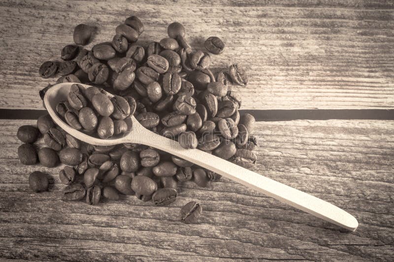 Black coffee and wooden spoon with coffee grains are on vintage wooden background