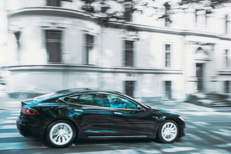 Black Color Tesla Model S 100d Car Fast Drive In Summer City Street. The Tesla Model S Is A Full-sized All-electric Five