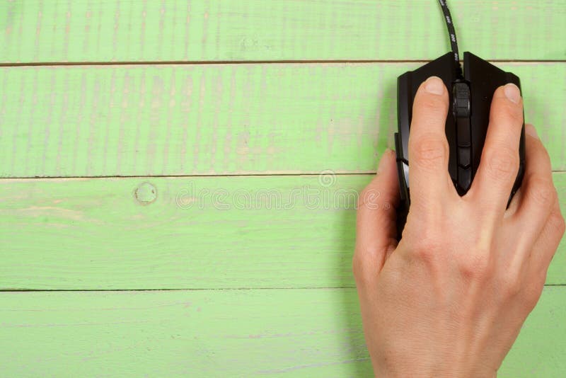Black computer mouse with a hand on a green wooden background with copy space for your text. Top view royalty free stock photography Black computer mouse with a hand on a green wooden background with copy space for your text. Top view royalty free stock photography