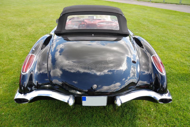 Black corvette convertible on green meadow