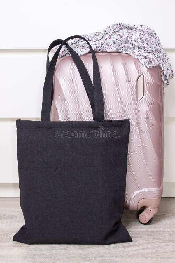 Black cotton eco tote bag with a travel suitcase, design mockup. Handmade shopping bags.