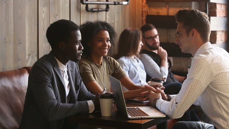 Black couple talking agreeing with caucasian businessman in coffee shop