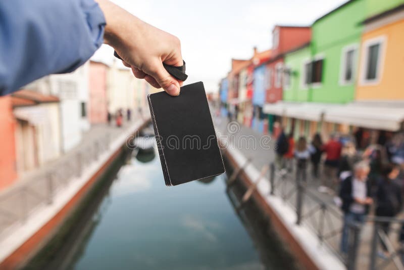 Black empty card in the hands of a young man on the background of colored houses and canal of Burano island, Venice royalty free stock images Black empty card in the hands of a young man on the background of colored houses and canal of Burano island, Venice royalty free stock images