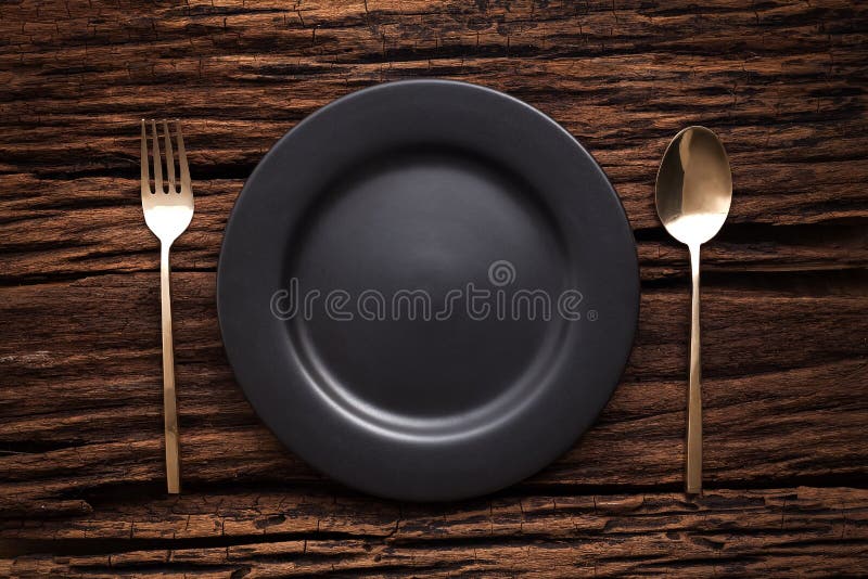 Black empty plate fork spoon on wooden table background stock photo