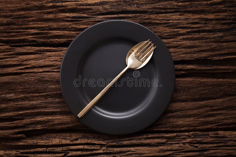 Black empty plate fork spoon on wooden table background royalty free stock photography