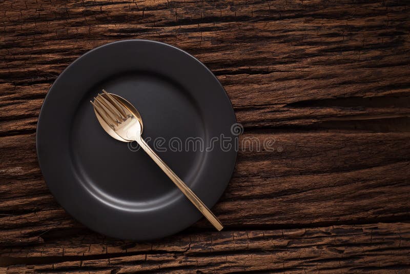 Black empty plate fork spoon on wooden table background stock photography