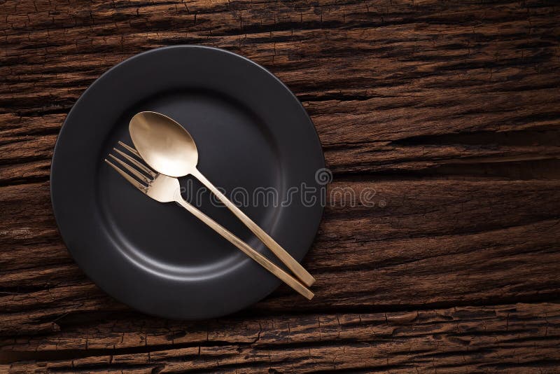 Black empty plate fork spoon on wooden table background stock image