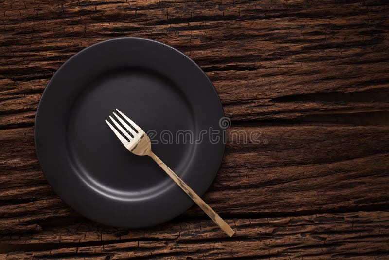 Black empty plate fork on wooden table background royalty free stock photo
