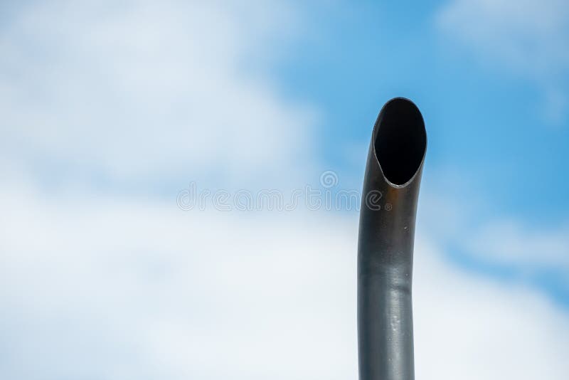 The black exhaust pipe of a truck against the blue sky. Environmental protection and reduction of emissions of harmful substances