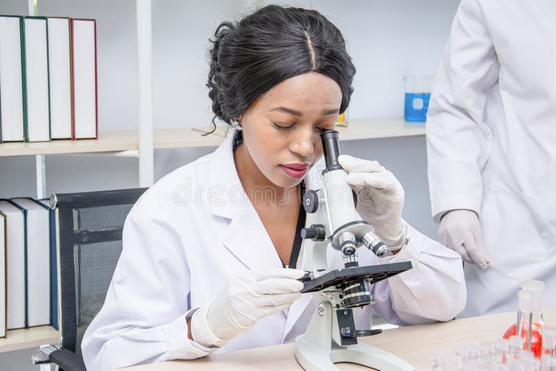 Black female scientist use microscope and test tube chemical ingredient to conduct research in laboratory,test sample antibiotics and future food use in medical development for people
