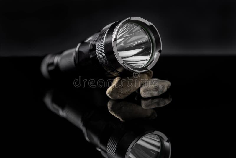 Black flashlight on stones mirroring on black background. Useful for adventure, military, hunting, outdoor, protection, security, background presentation. Mirroring object stock images, royalty-free photos and pictures