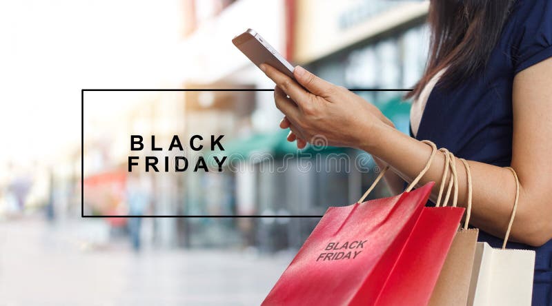 Black Friday kvinna som använder bärande shoppingpåsar för smartphone arkivbilder Black Friday kvinna som använder bärande shoppingpåsar för smartphone arkivbilder
