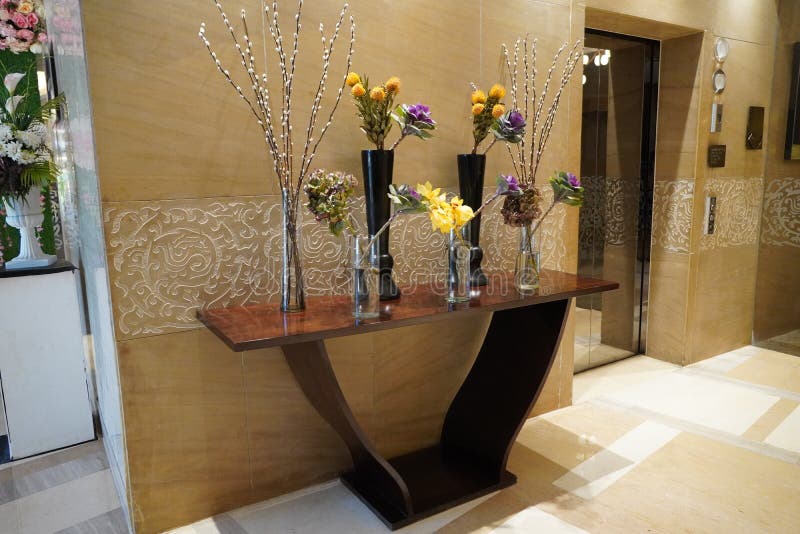 Black and Glass vases with flowers inside are put on the antique table for interior decoration in a hotel lobby. Theyâ€™re decorative items for vintage classic design in house, hotel, restaurant