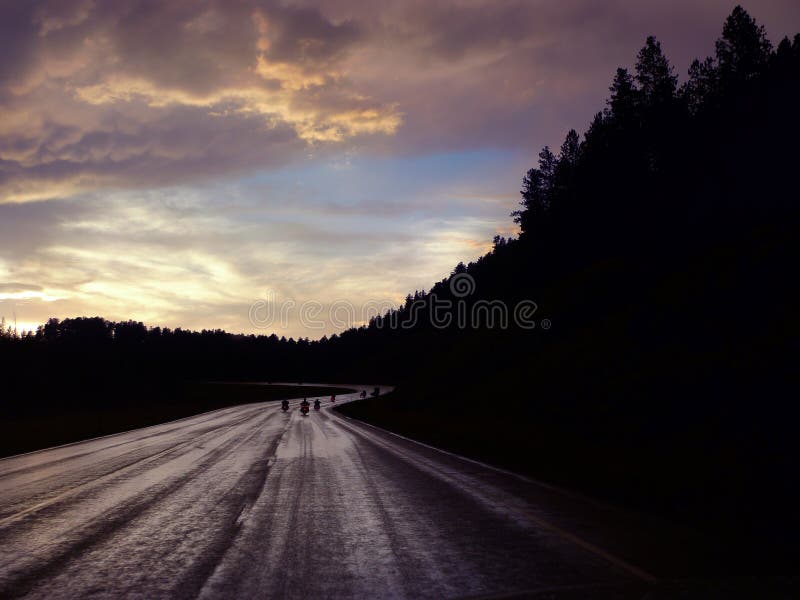 Black Hills motorcyclists ride at sunset on wet road