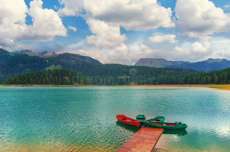 Black lake in Durmitor national park in Montenegro, Europe. Mountain, forest and beach on blue cloudy sky a sunny day at sunset.