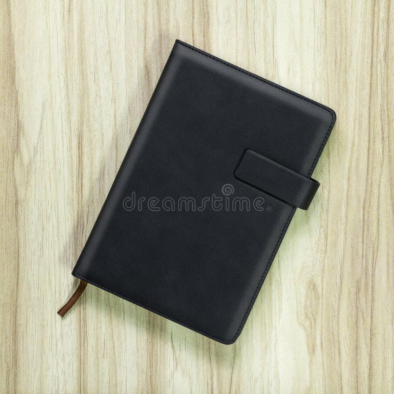 Black leather book on wood background. Blank template of hardcover book stock photos