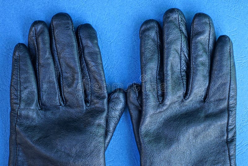 Black leather gloves lie on a blue table royalty free stock image