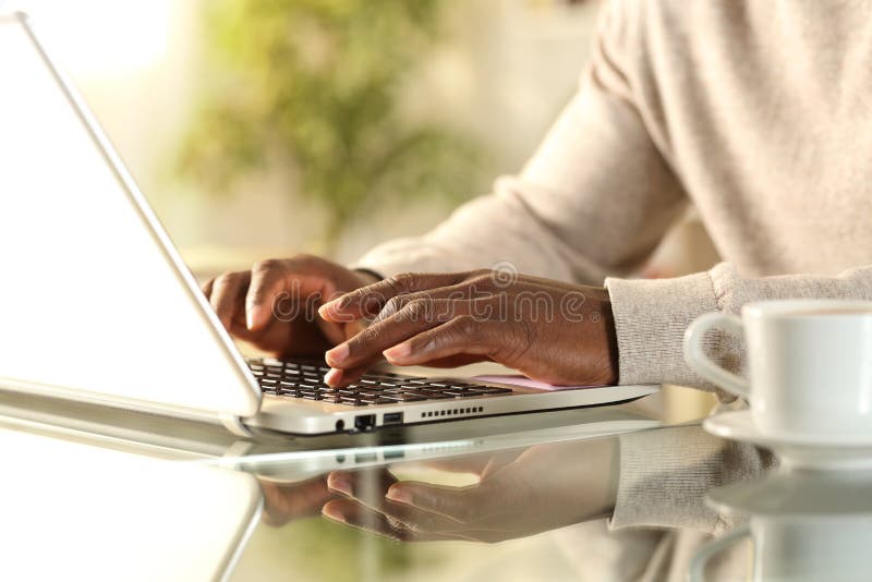 Close up of black man hands typing on a laptop sitting on a desk at home. Close up of black man hands typing on a laptop sitting on a desk at home