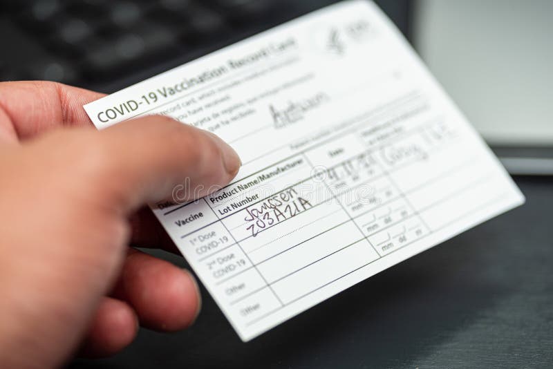 Black man holding a Janssen covid 19 vaccination record in hand