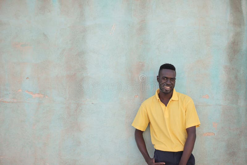 Black Man in a Yellow Shirt Smiling Behind the Wall Stock Photo Image