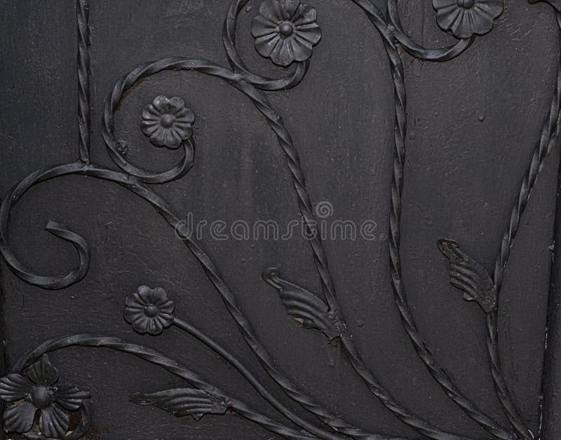 Black metal gate panel with flower design background texture. Close up of black metal gate panel with twisted rods as stems with flowers design