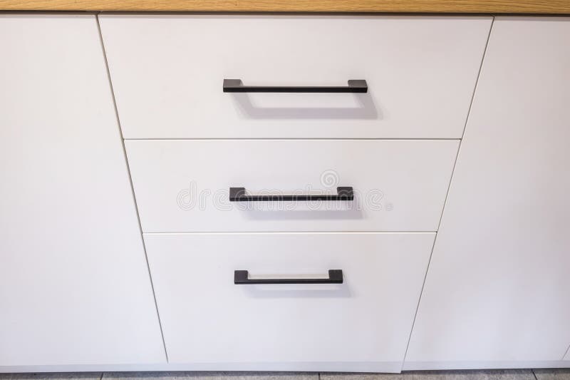 black metal handles on white nightstand cabinets and drawers on kitchen