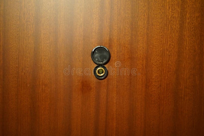 Black Peephole in the Door. the Door is Mahoganycolored. Stock Photo